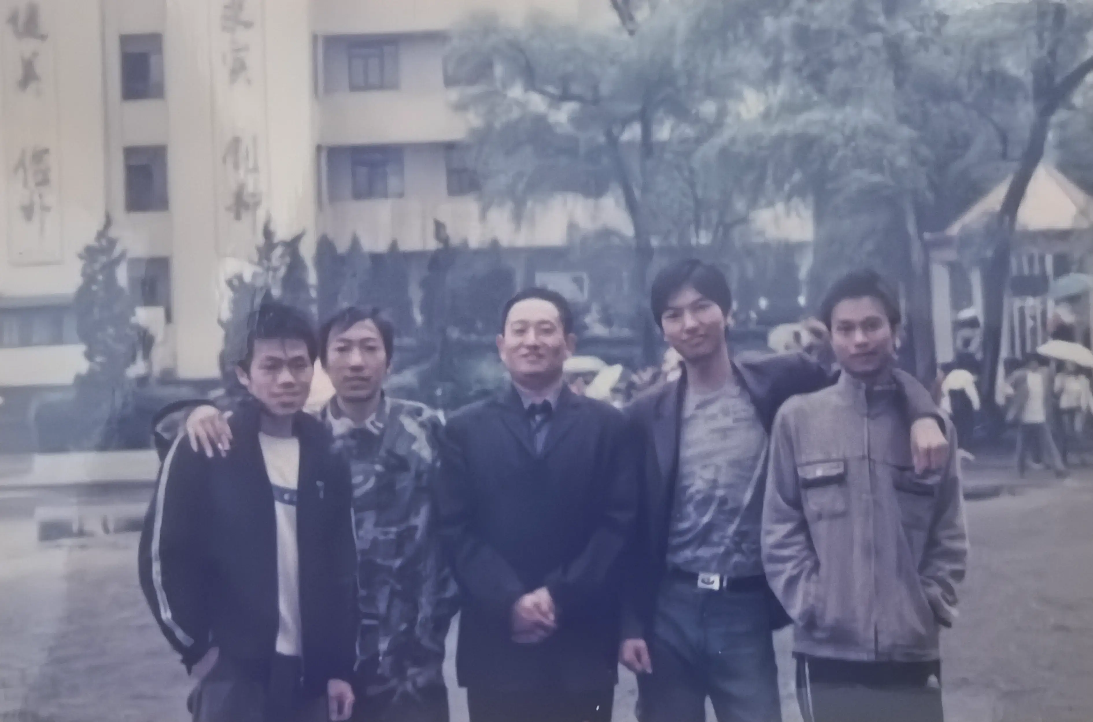姜南、吴增明、陆云、罗文跟班主任何平老师在教学楼前拍的。四个男生站在何老师身边有点拘谨,何老师倒是笑得很自在。蓝白校服穿了三年,现在看着倒觉得挺好看。